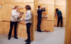 Female Tutor With Trainee Electricians In Workshop Studying For Apprenticeship At College