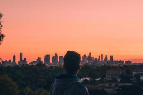 Rear View Of Man And Buildings Against Sky During Sunset