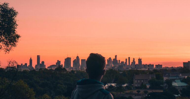Rear View Of Man And Buildings Against Sky During Sunset